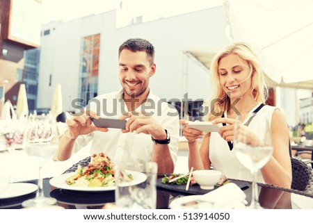 love, date, technology, people and relations concept - happy couple with smatphone taking picture of food at restaurant terrace