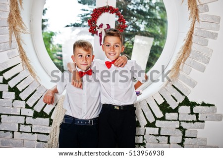 Two brothers posed at studio room background round window
