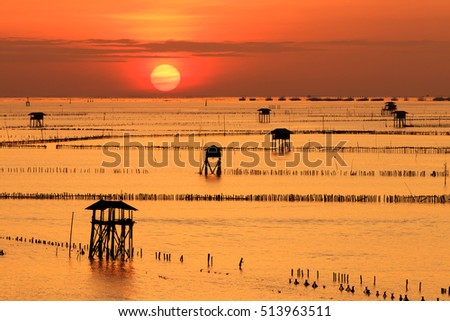 Silhouette of man paddling boat at sunrise Bang tabun ,Phetchaburi ,Thailand. Gulf of Thailand. Cottage located in the sea. The accommodation of the fishermen. Bangtabun ,Phetchaburi ,Thailand