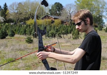 Young adult man getting his bow and arrow ready for archery Royalty-Free Stock Photo #51397249
