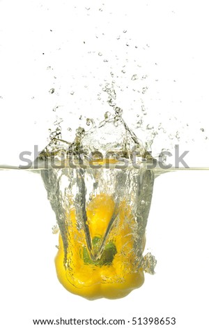 Yellow Pepper splashing on water in white background.A background of bubbles forming in blue water after yellow pepper are dropped into it.