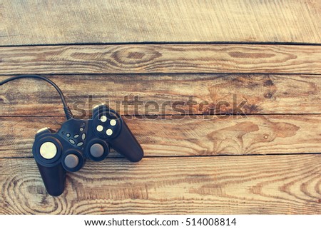 Video game controller on old wooden background. Toned image. Top view. 