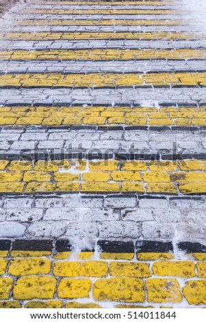 Yellow white zebra crossing snowy cobblestone background
