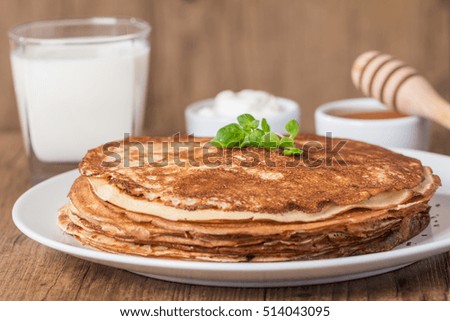 Stack of pancakes sour cream, milk and honey on wooden table