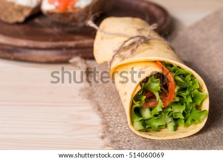 fresh tortilla wraps with vegetables on wooden background