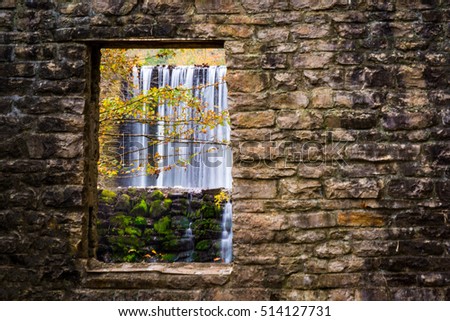 A picturesque waterfall at Mirror Lake Arkansas is framed by a stone window that is an old water powered mill.