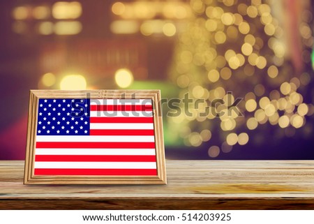 American flag in photo frames on wooden table with abstract christmas light night background