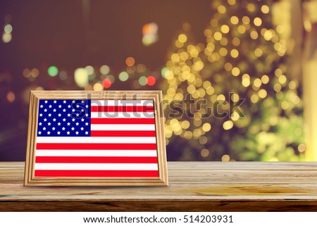 American flag in photo frames on wooden table with abstract christmas light night background