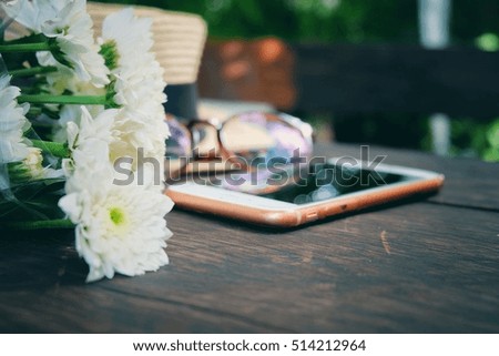 Blurry and soft focus Bouquet of white flowers and mobile phone on wooden background.