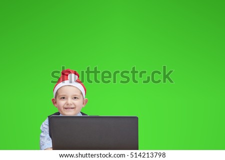 A child wearing in cap of Santa Claus looking at a laptop