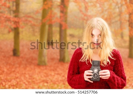 Portrait of woman in fall autumn forest park with old vintage camera.