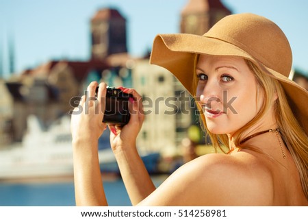 Tourism, artistic, elegant fashion. Woman in elegant outfit and sun hat taking pictures with camera