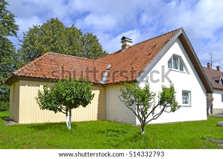 Beautiful house with a tiled roof and two small sweet tree in Estonia.