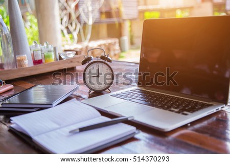 business schedule concept with black alarm clock with blank screen notebook or laptop on wooden floor with free copy space for yout text ideas