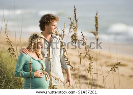 Happy young pregnant woman at beach with husband