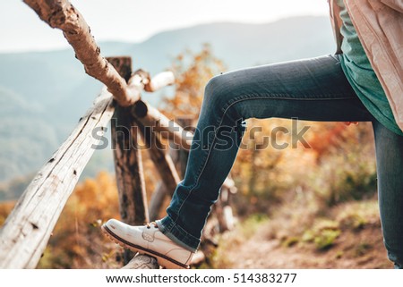 Woman resting on mountain trail by wooden fence