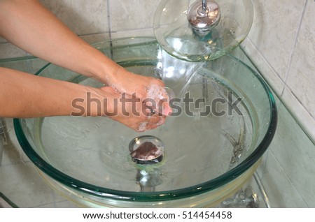 Washing hands under running tap water over the sink