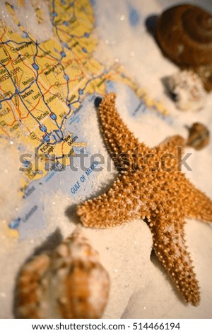 Close-up shot of sand and seashells pictured with The Gulf of Mexico in an atlas.