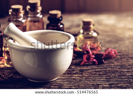 mortar and bottle of aroma essential oil with dry flower on wooden table, spa concept.vintage color tone. Royalty-Free Stock Photo #514476565