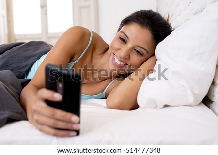 young beautiful hispanic woman relaxed using internet mobile phone sending message at home bedroom smiling happy in bed having telephone conversation in communication concept