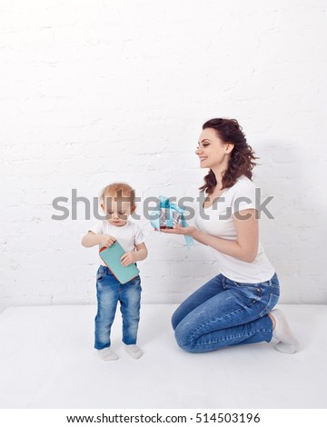 Mother and daughter are holding wallet and a gift. Mother and daughter dressed in jeans and white T-shirts. Family look.