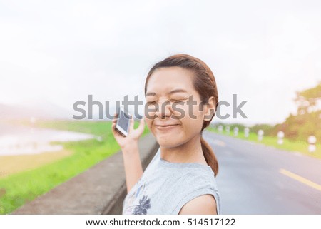 young Woman hand holding smart phone against spring green background at morning with happy action.