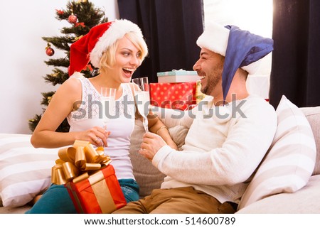 Picture of happy smiling Christmas couple celebrating New Year at home all together. Cheerful lady is satisfied by her husband's present or gift for New Year or Christmas.