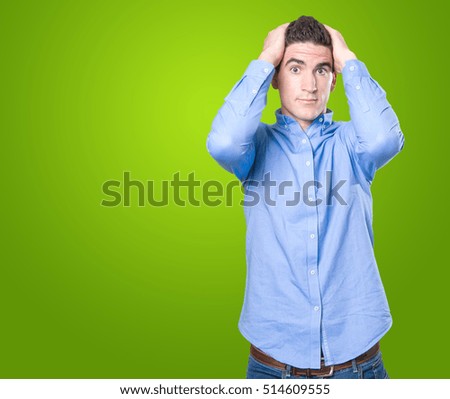 Depressed young man with his hands on his head on green background