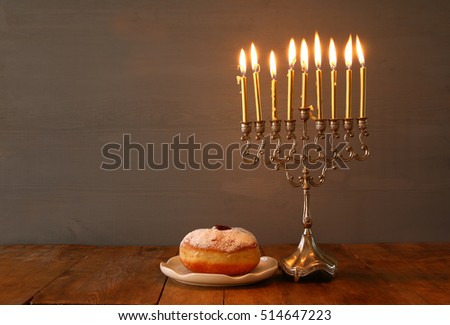 Low key Image of jewish holiday Hanukkah with menorah (traditional Candelabra) and donut