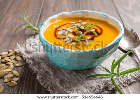 Roasted pumpkin soup with balsamic and pumpkin seeds on wooden background, close up