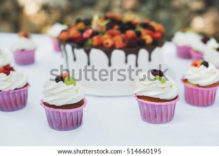 Delicious fruit cake with cupcakes for a happy birthday
