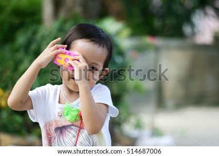 Cute asian child girl take photo by toy camera .Selective Focus