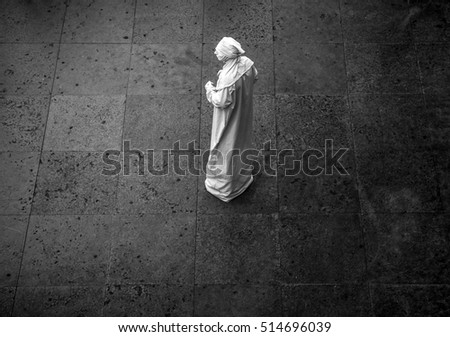 Black-white photo of street performance of actor stylized in white clothes and mask.
