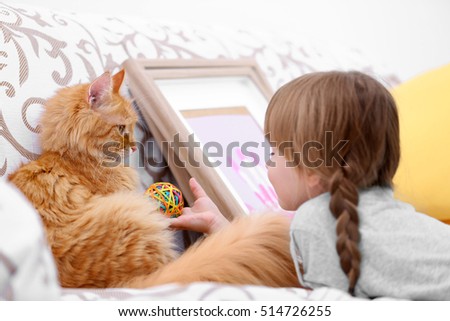 Cute little girl and red cat on sofa, closeup