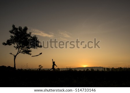 Silhouette a girl playing kite on sunrise in the fields