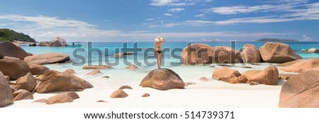 Woman wearing black bikini and beach hat, enjoying amazing view on Anse Lazio beach on Praslin Island, Seychelles. Summer vacations on picture perfect tropical beach concept.