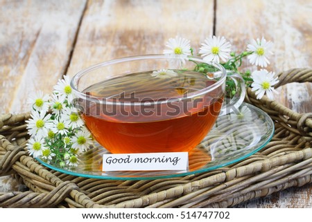 Good morning card with chamomile tea in transparent cup with fresh chamomile flowers
