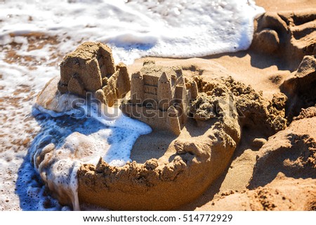 waves wash away sand castles on the beach the sea Royalty-Free Stock Photo #514772929