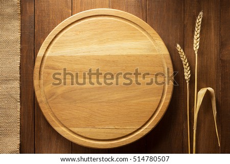 ears of wheat and cutting board on wooden background