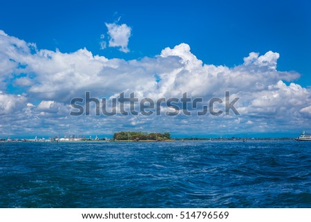 Vast expanses of water. The bright sky and large cloud. Bright buildings on the water background. Seascape.