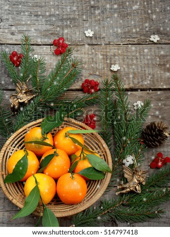 Basket of ripe mandarins, spruce branches and christmas toy on a wooden background. selective focus. copy space