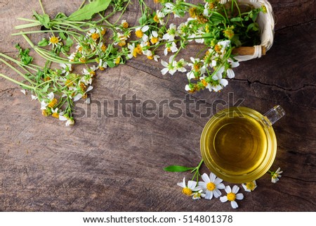 cup of chamomile tea with chamomile flowers on wooden planks with copy space.