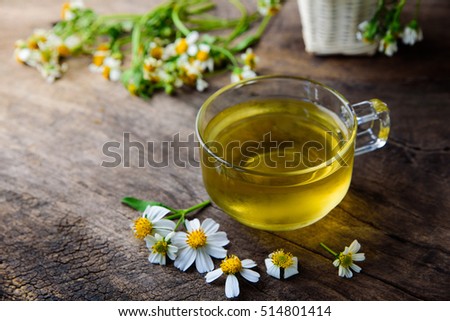cup of chamomile tea with chamomile flowers on wooden planks with warm tone