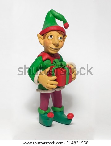 Plasticine character. Funny Christmas elf holding a gift. Isolated on white background Royalty-Free Stock Photo #514831558