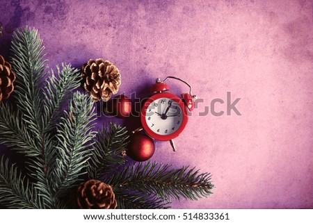 Christmas alarm clock and pine branch on violet background