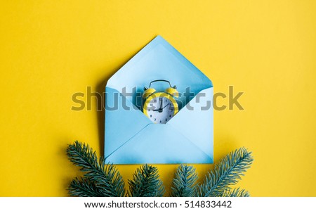 Blue christmas envelope and retro alarm clock on yellow background