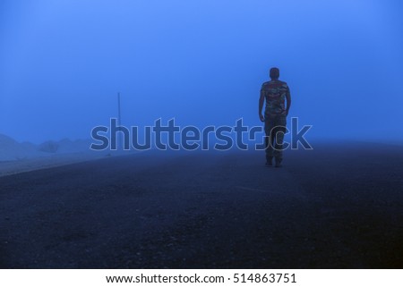 Man walking in to the mist wearing a camouflaged clothing 