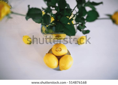 Lemons and golden wedding rings next to the vase