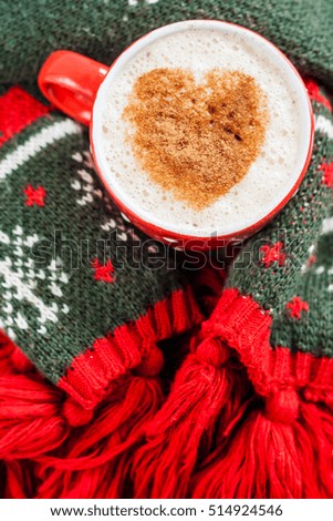red cup of coffee and heart patterned green scarf wrapped.