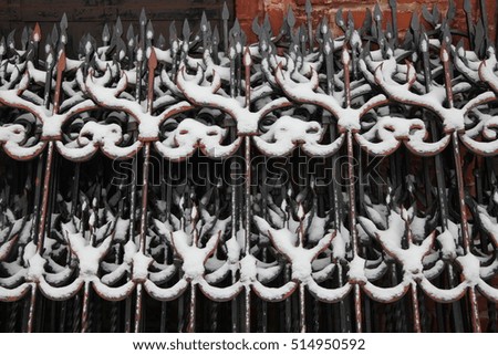 Metal decorative fence in the snow. The part of a metal fence covered with snow close-up